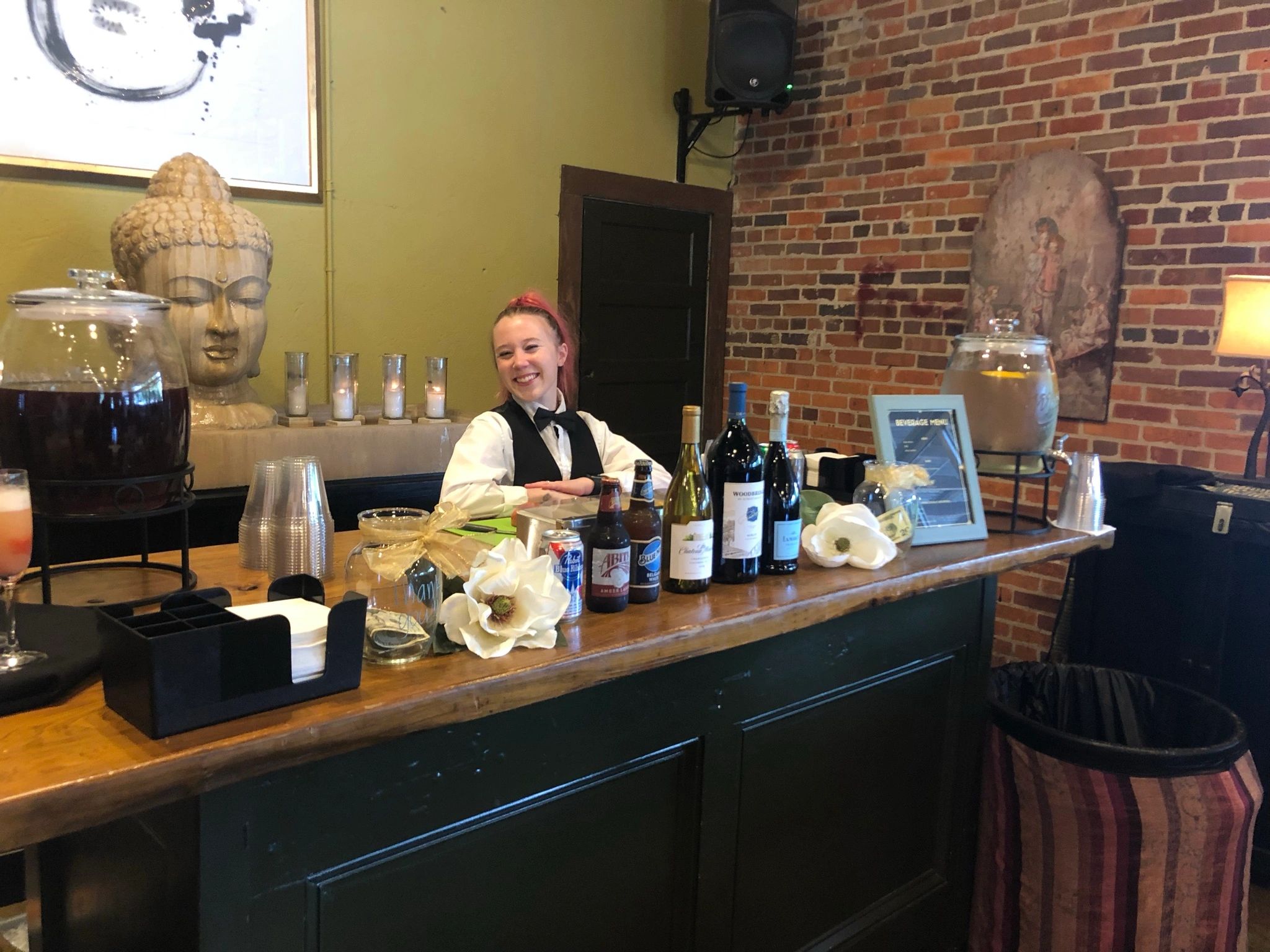 Smiling bartender behind a decorated counter.