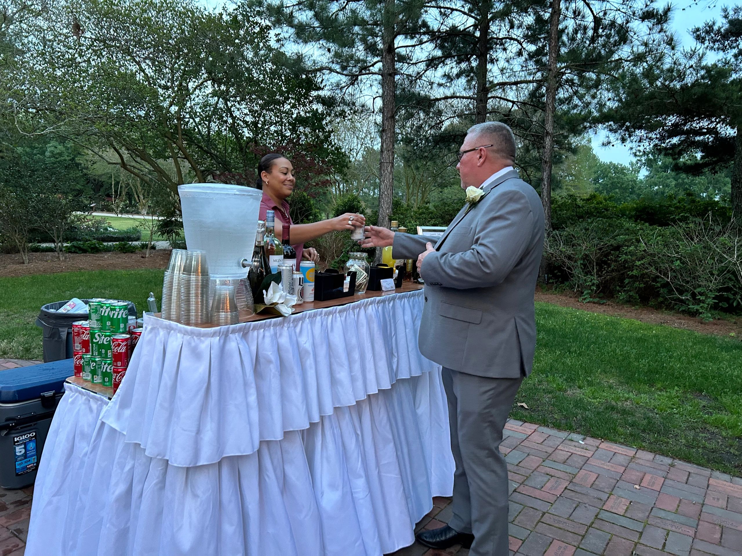 Man receiving drink at outdoor bar station.