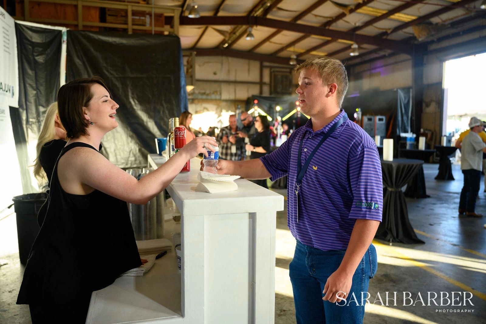 Two people exchanging drinks at event.