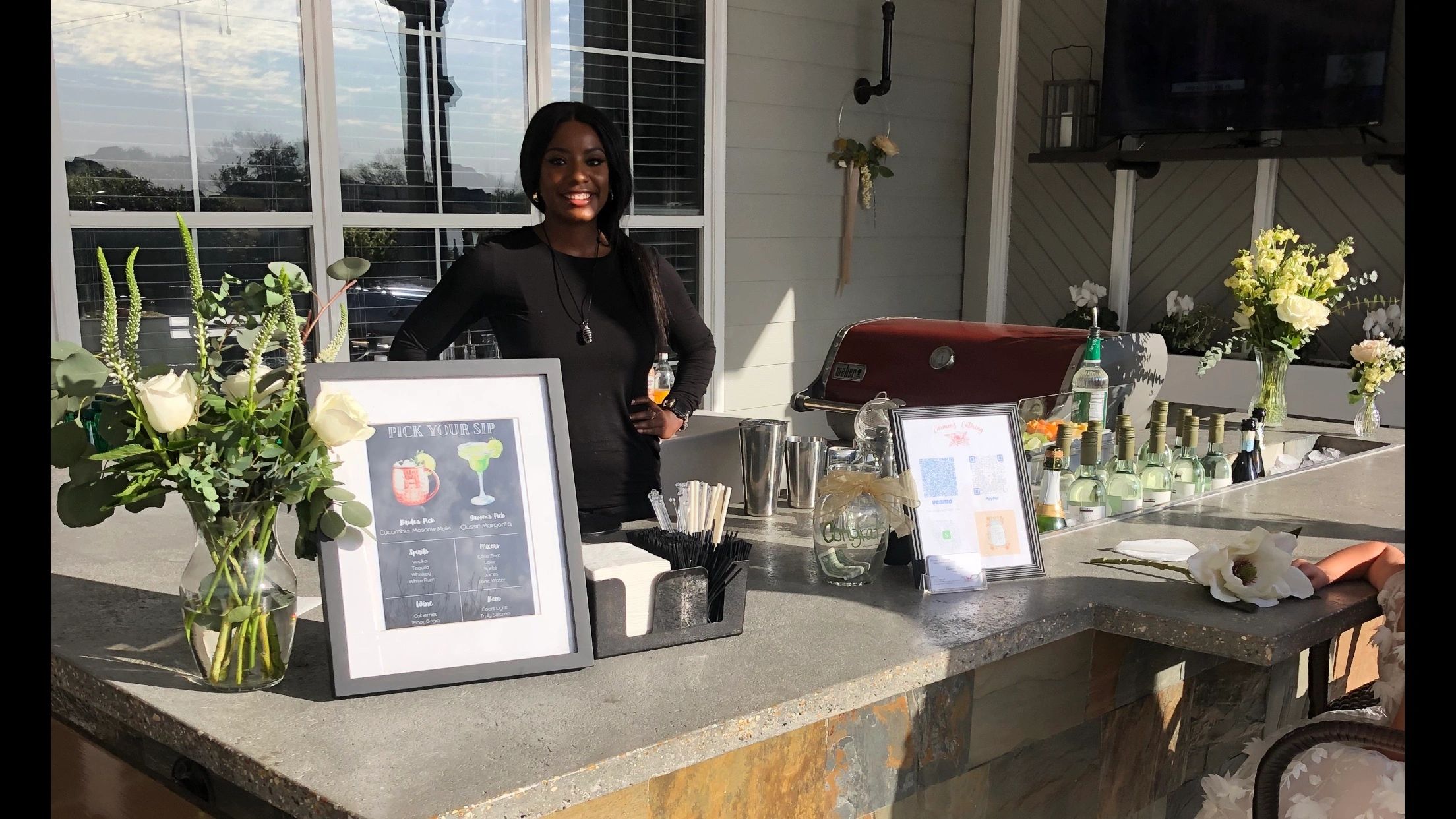 Bartender smiling behind outdoor bar setup.