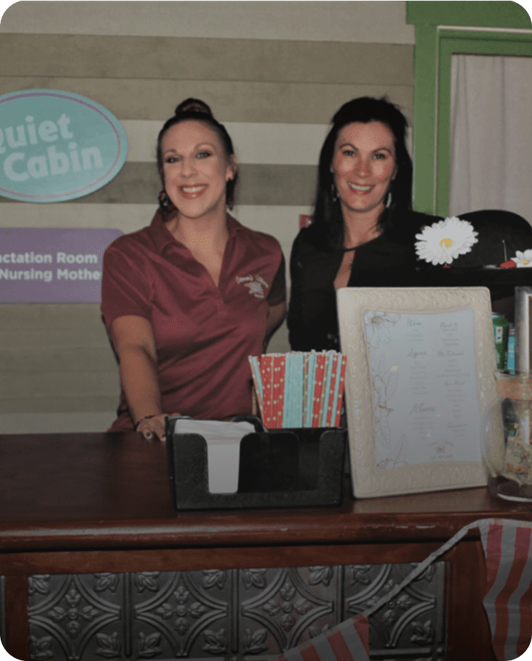 Two women smiling behind a counter.