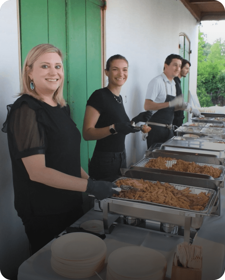 People serving food at a buffet table.