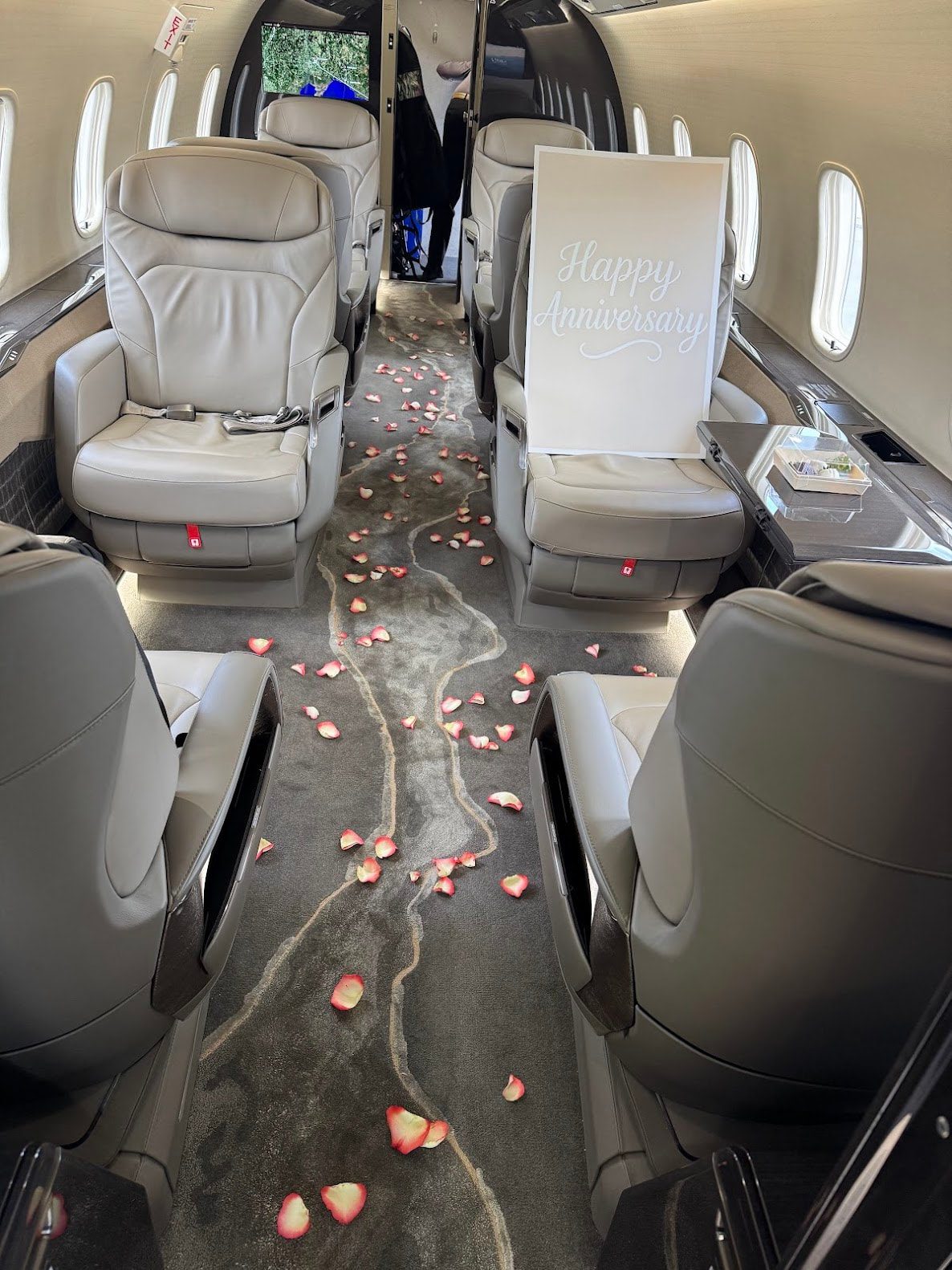 Private jet interior with rose petals scattered.