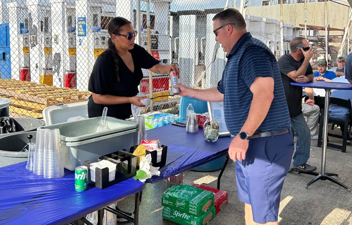 Person receiving soda from vendor at outdoor event