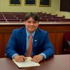 Smiling man in blue suit signing document