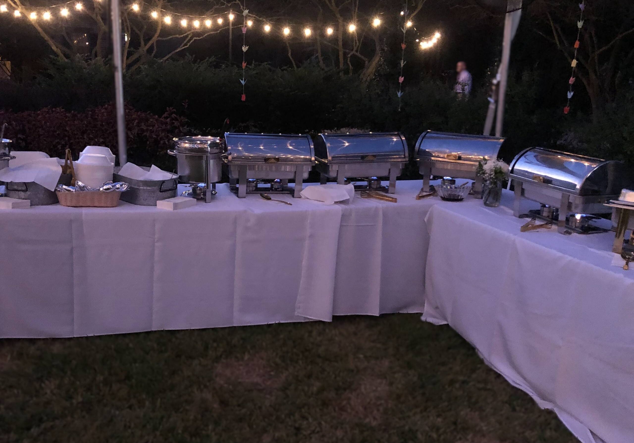 Outdoor buffet with chafing dishes and string lights