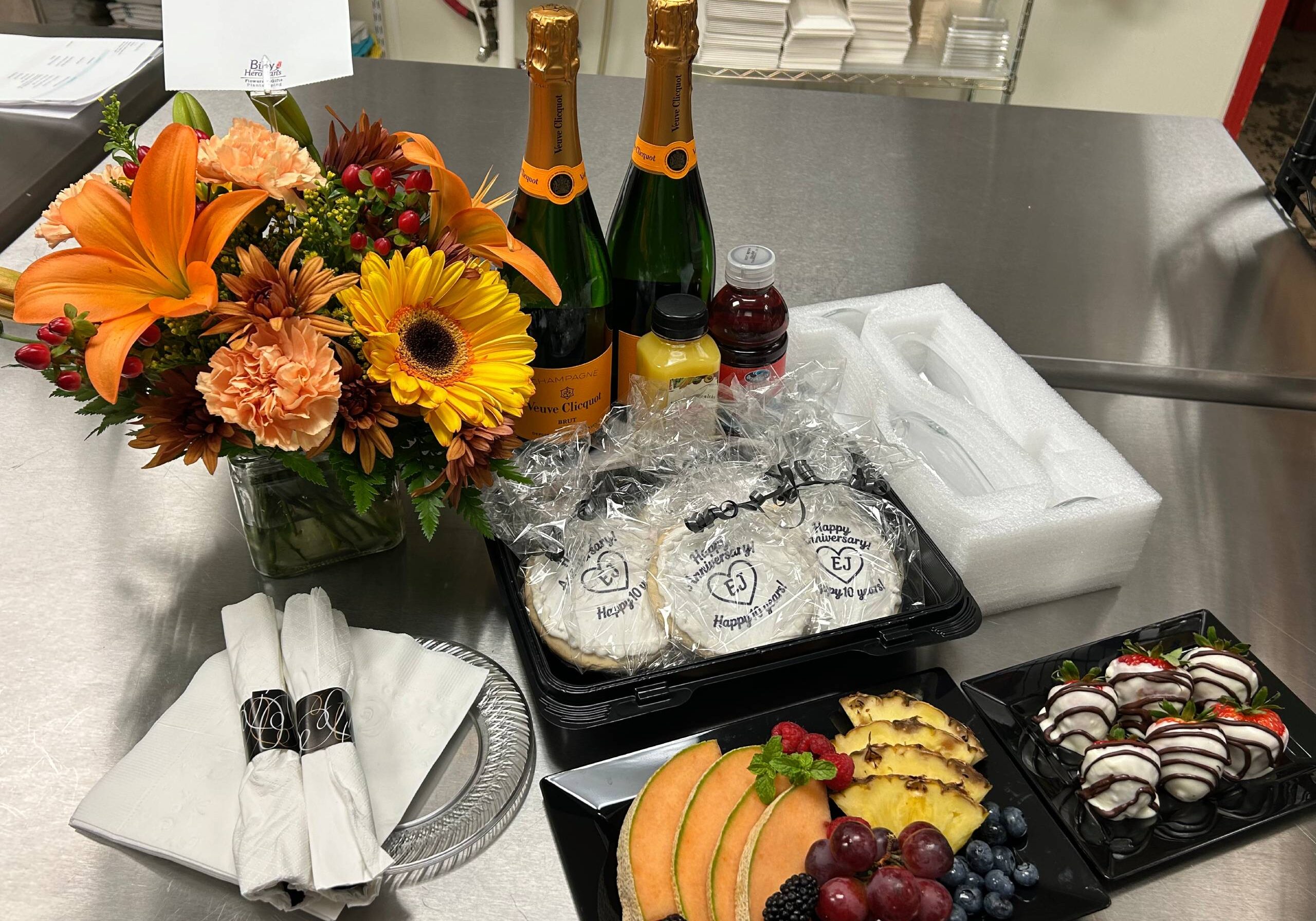 Flowers, fruit platter, pastries, and champagne bottles