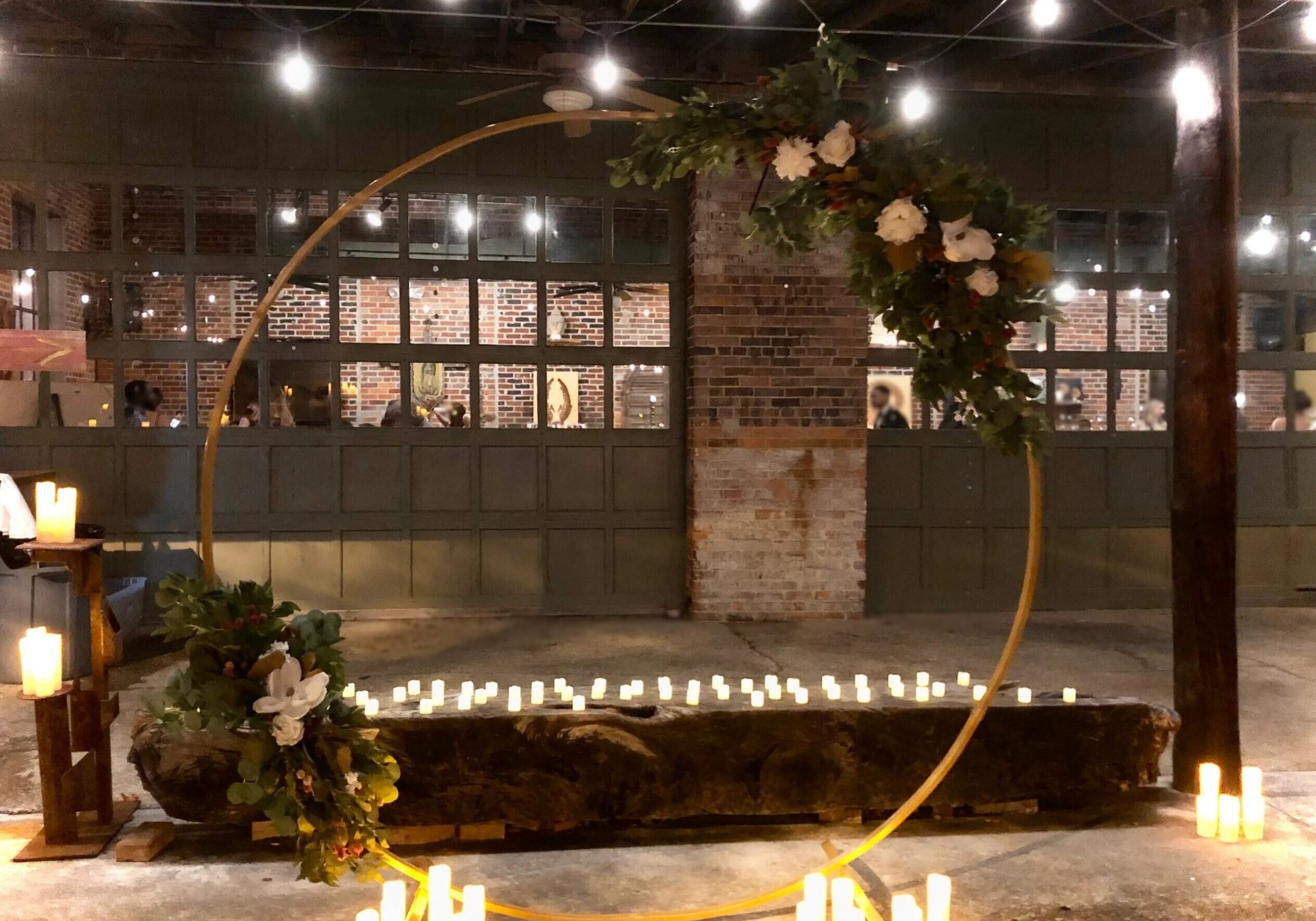 Gold circular floral arch surrounded by candles