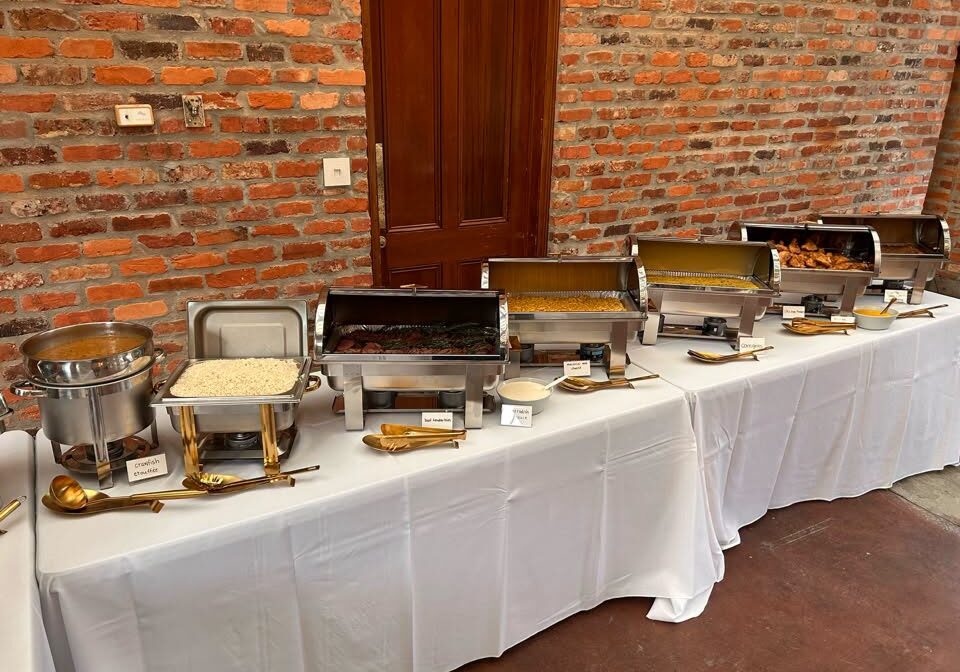 catering table set up with white linens and silver serving dishes